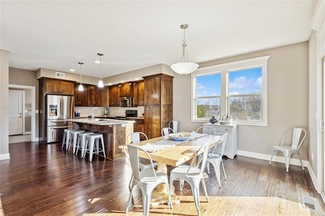 dining space with dark wood-style floors, visible vents, and baseboards