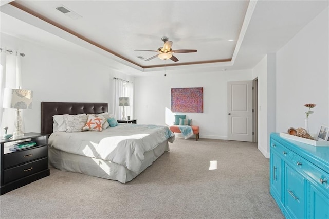 carpeted bedroom featuring visible vents, a raised ceiling, baseboards, and a ceiling fan