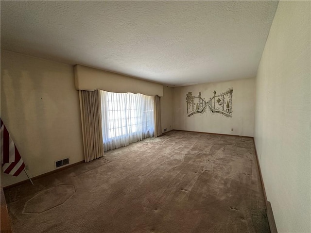 carpeted empty room with visible vents, a textured ceiling, and baseboards