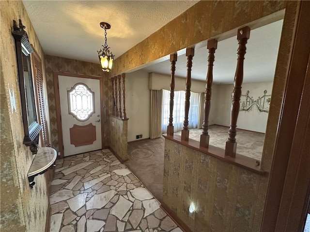 foyer with a textured ceiling, stone finish flooring, plenty of natural light, and visible vents