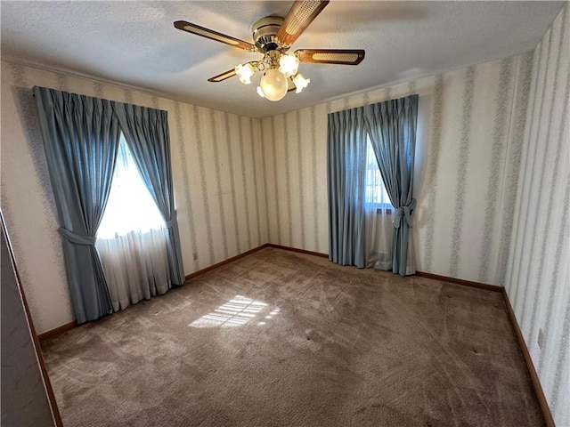 carpeted spare room featuring ceiling fan, a textured ceiling, baseboards, and wallpapered walls