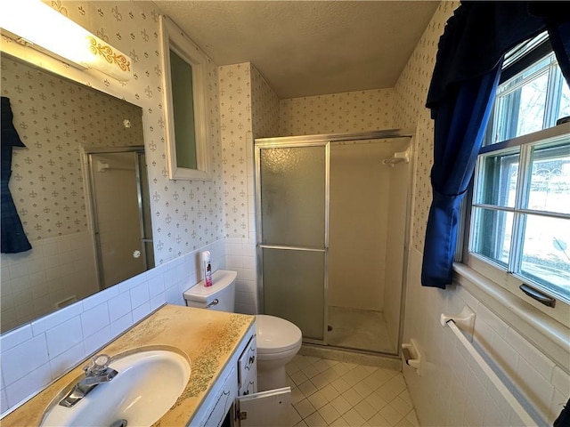 bathroom featuring tile patterned flooring, vanity, wainscoting, a shower stall, and wallpapered walls