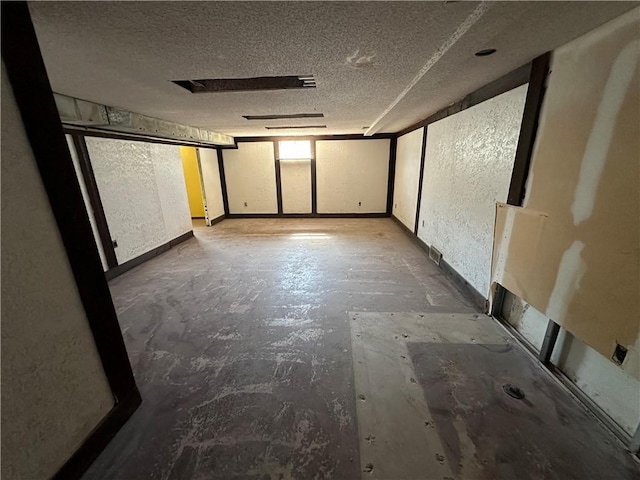 unfurnished room featuring unfinished concrete floors, a textured ceiling, and a textured wall