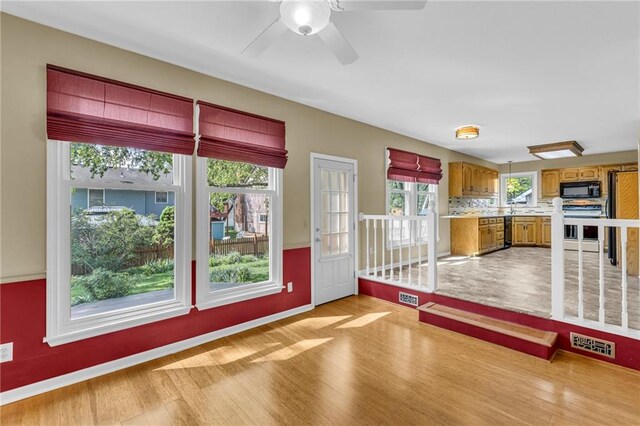 interior space with visible vents, brown cabinetry, light wood-style floors, light countertops, and black appliances
