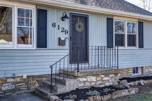 doorway to property featuring a shingled roof