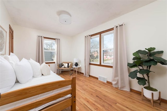 bedroom featuring light wood-style floors, visible vents, and baseboards