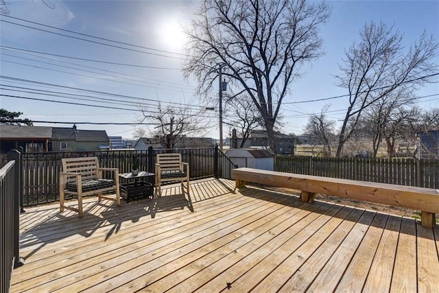 wooden deck featuring fence, an outbuilding, and a shed