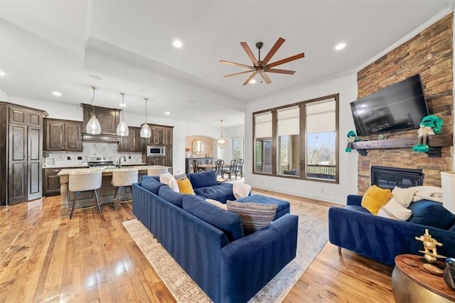 living room with light wood-type flooring, a fireplace, baseboards, and recessed lighting