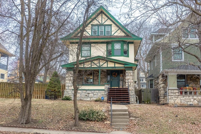 view of front of home with a porch, stone siding, fence, and stairway