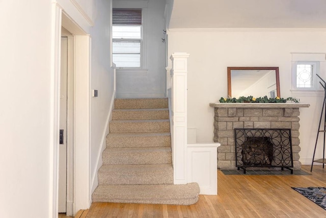 staircase with a fireplace with flush hearth and wood finished floors