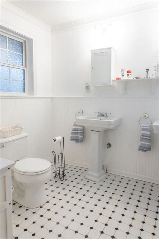 bathroom with ornamental molding, wainscoting, toilet, and tile patterned floors