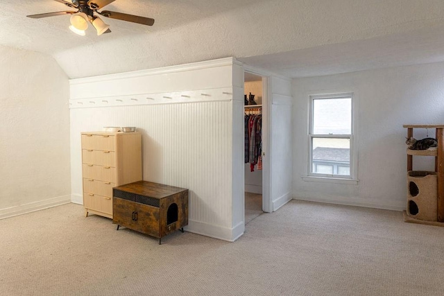 carpeted bedroom featuring a closet, vaulted ceiling, a textured ceiling, ceiling fan, and baseboards