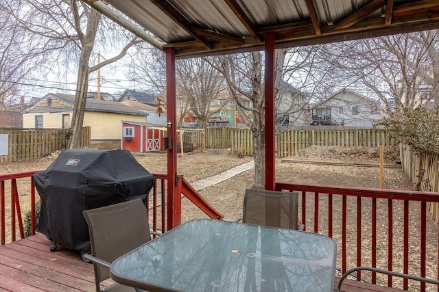 wooden deck with a fenced backyard, area for grilling, an outdoor structure, a shed, and outdoor dining space