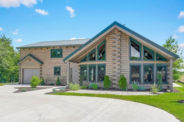 rear view of house with metal roof, an attached garage, concrete driveway, log siding, and a standing seam roof