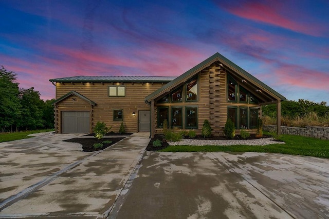 log cabin featuring driveway, a standing seam roof, an attached garage, and metal roof