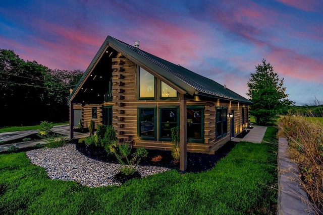 property exterior at dusk featuring metal roof, a lawn, and log exterior