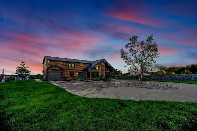 view of front of property with a lawn, log exterior, concrete driveway, metal roof, and a standing seam roof