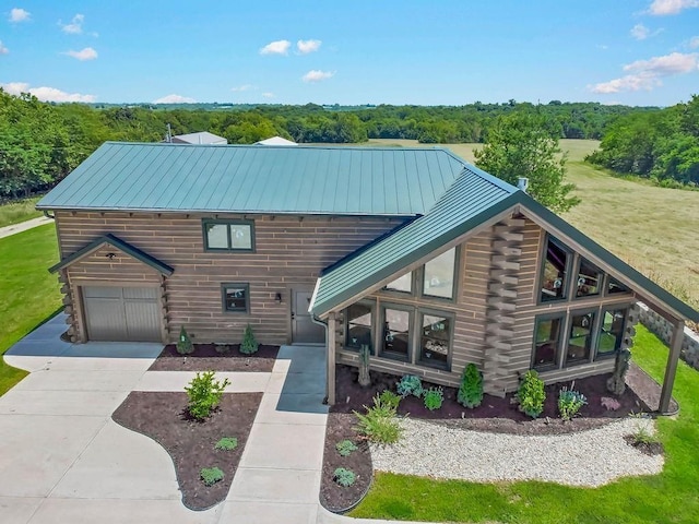 view of front of home featuring a standing seam roof, metal roof, log exterior, a garage, and driveway