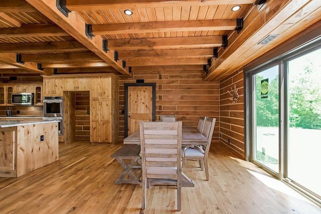 dining space featuring wooden ceiling, light wood finished floors, wooden walls, and beamed ceiling