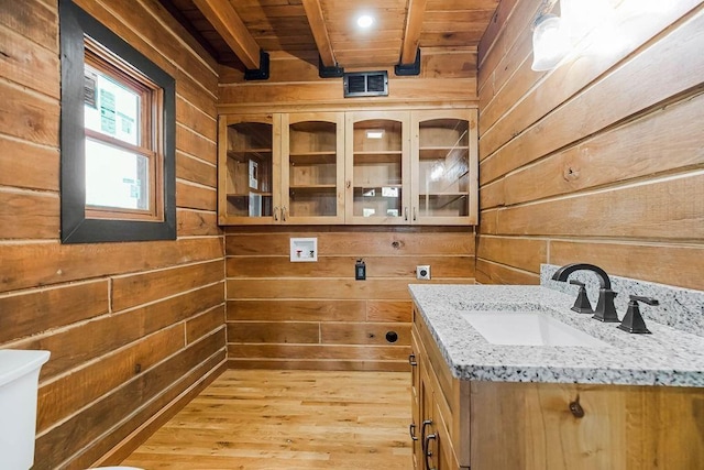 interior space with wooden walls, visible vents, wooden ceiling, wood finished floors, and vanity