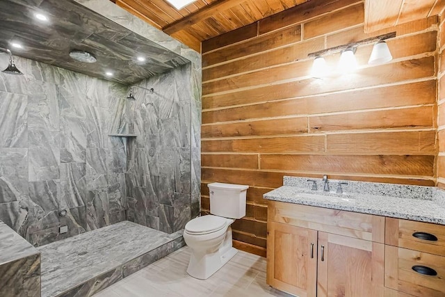 full bath featuring wooden walls, tiled shower, vanity, and toilet