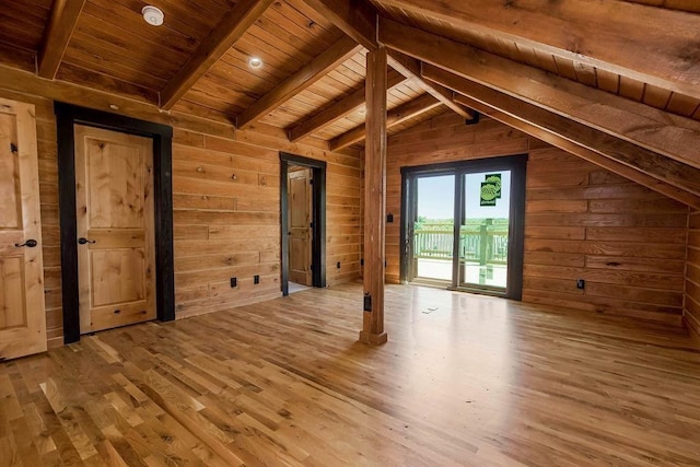 interior space featuring wooden walls, lofted ceiling with beams, wooden ceiling, wood finished floors, and access to exterior