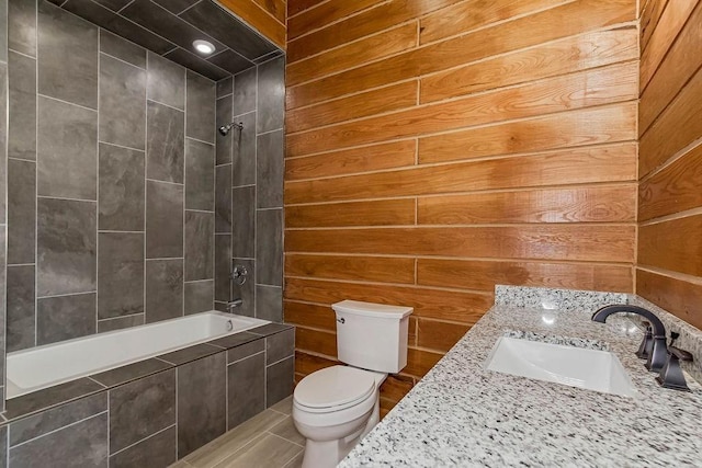 full bathroom with tiled shower / bath combo, a sink, wooden walls, and toilet