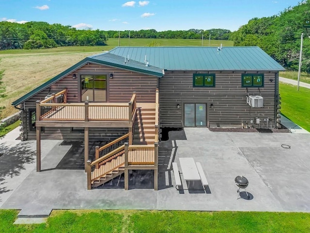 back of property featuring stairway, metal roof, a deck, a patio area, and central AC