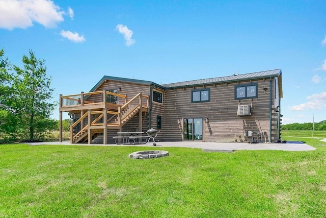 rear view of house featuring a lawn, an outdoor fire pit, a standing seam roof, a wooden deck, and stairs