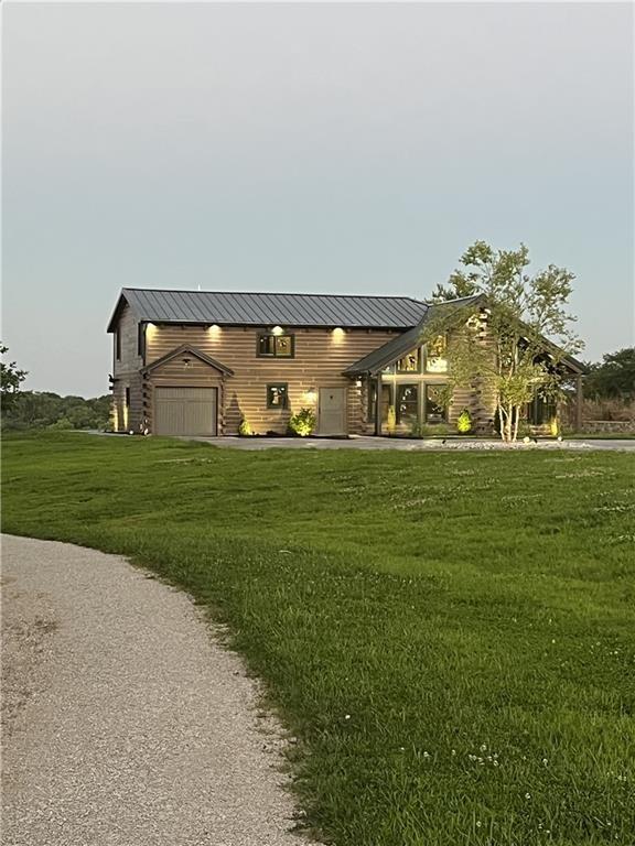 view of front facade featuring a garage, a standing seam roof, metal roof, and a front lawn