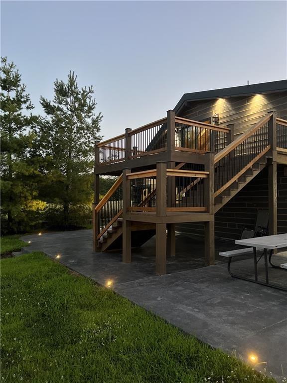 rear view of property featuring a patio area, stairs, a lawn, and a wooden deck