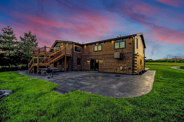 back of house at dusk with a patio area, stairs, a deck, and a yard