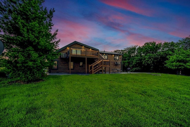 back of house at dusk with a wooden deck, log veneer siding, stairway, and a yard