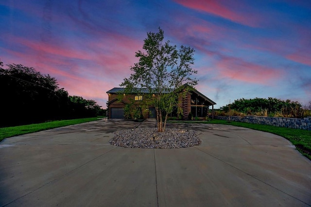 view of front of property featuring driveway, an attached garage, and metal roof