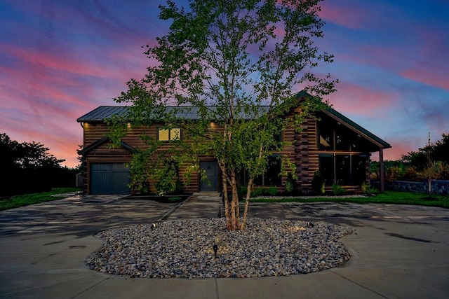 log cabin with a garage, metal roof, driveway, and log exterior