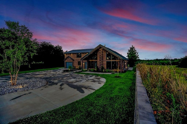 log cabin with metal roof, log exterior, concrete driveway, and a yard