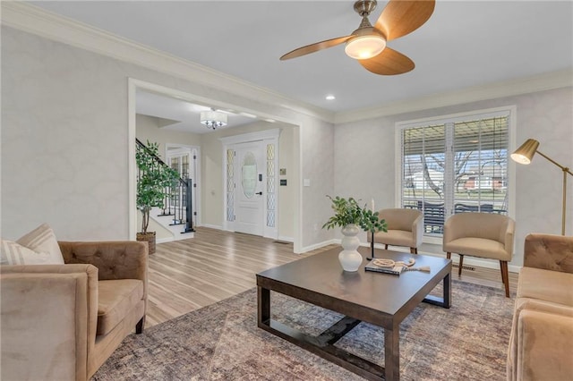 living room with stairway, wood finished floors, and ornamental molding