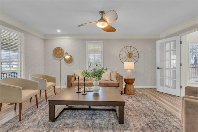 living room featuring ceiling fan, baseboards, wood finished floors, and ornamental molding