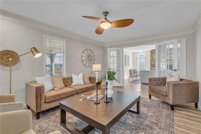 living area with crown molding, light wood-style flooring, and a ceiling fan