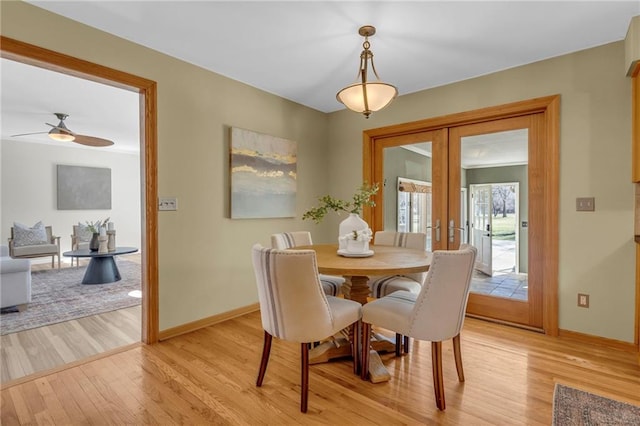 dining space with light wood finished floors, ceiling fan, french doors, and baseboards