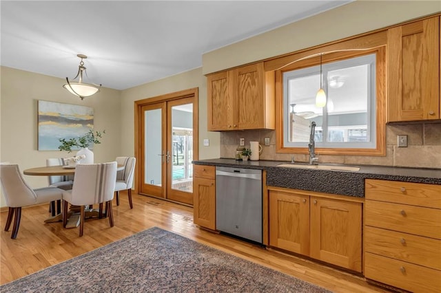 kitchen featuring a sink, stainless steel dishwasher, backsplash, french doors, and light wood finished floors