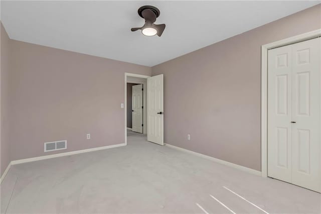 unfurnished bedroom featuring visible vents, light carpet, a ceiling fan, a closet, and baseboards