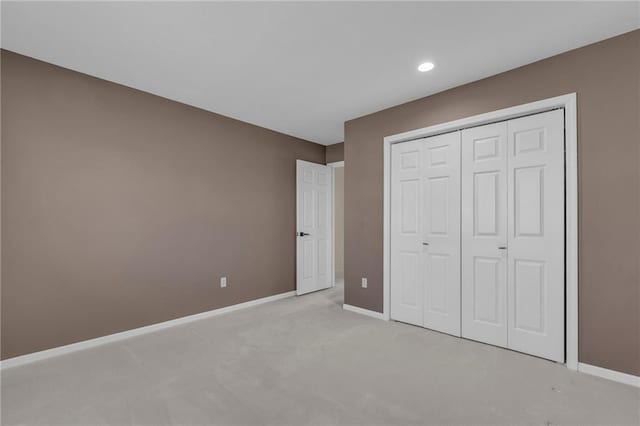 unfurnished bedroom featuring recessed lighting, light colored carpet, baseboards, and a closet