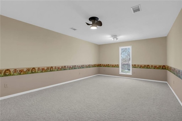 carpeted spare room with baseboards, visible vents, and ceiling fan