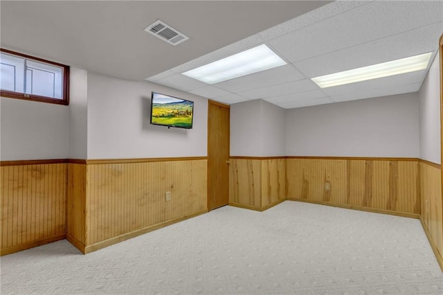 below grade area featuring a wainscoted wall, wood walls, carpet, and visible vents