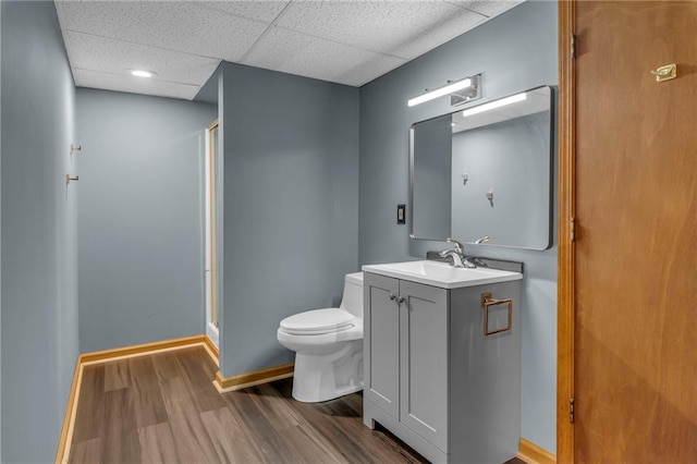 full bathroom featuring toilet, wood finished floors, baseboards, a shower stall, and a paneled ceiling