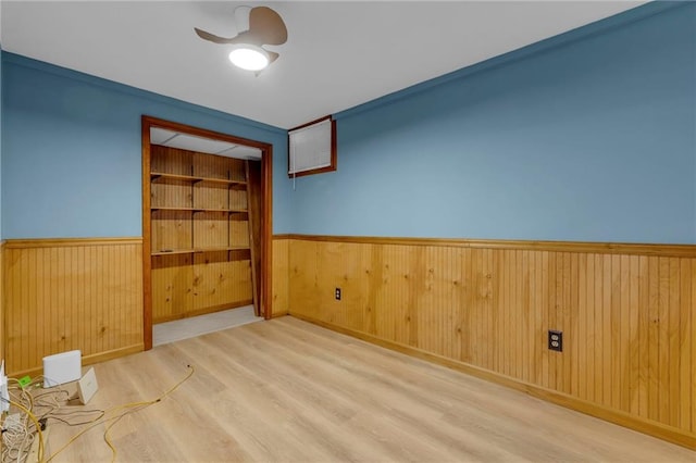 unfurnished room with wood finished floors, a wainscoted wall, and wood walls