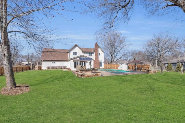 back of house featuring a gazebo, a yard, a chimney, and a fenced backyard