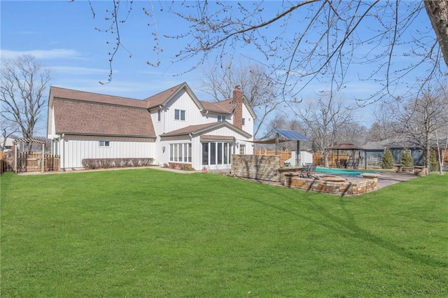 rear view of house featuring a gazebo, a yard, a chimney, and a shingled roof