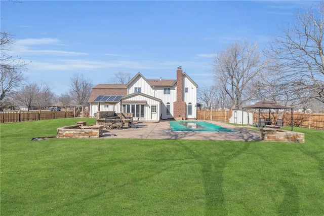 back of property with solar panels, a gazebo, a fenced backyard, and a patio area